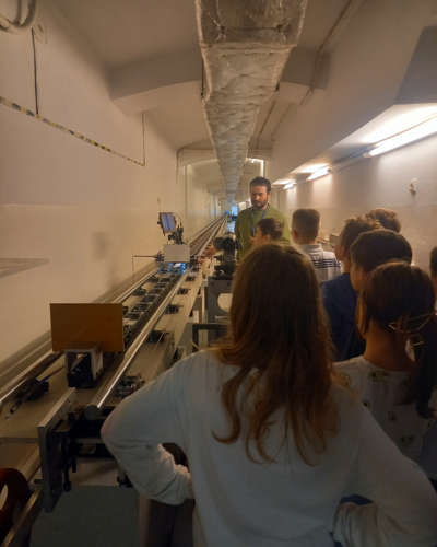  dzieci słuchają objaśnień metrologa z Laboratorium Długości na temat stanowiska pomiarowego o długości 50 metrów znajdującego się w podziemiach Głównego Urzędu Miar