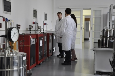  Grupa kilku osób w białych fartuchach - pracowników laboratorium stoi przy stanowisku państwowego wzorca jednostki miary temperatury.