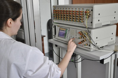 Stanowisko pomiarowe wzorca roboczego w zakresie od -80 °C do 550 °C Kobieta w białym fartuchu naciska przyciski urządzenia na stanowisku pomiarowym wzorca roboczego w zakresie od -80 °C do 550 °C