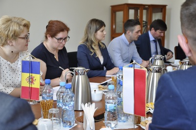  Na zdjęciu kilka osób siedzi przy stole - są to członkowie delegacji mołdawskiej. Na stole butelki z wodą, laptopy, inne materiały.
